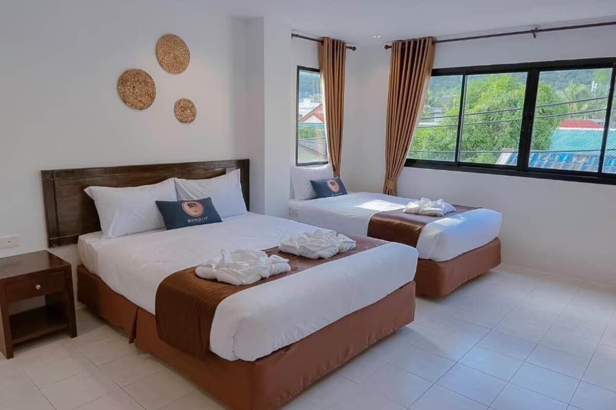 A hotel room with two beds, a nightstand, and a window with curtains.