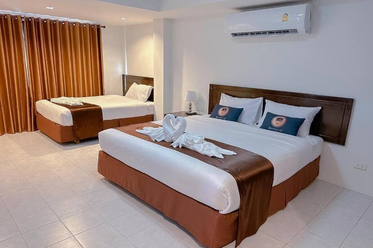 A hotel room with two beds, a large window, an air conditioning unit, and a curtain.