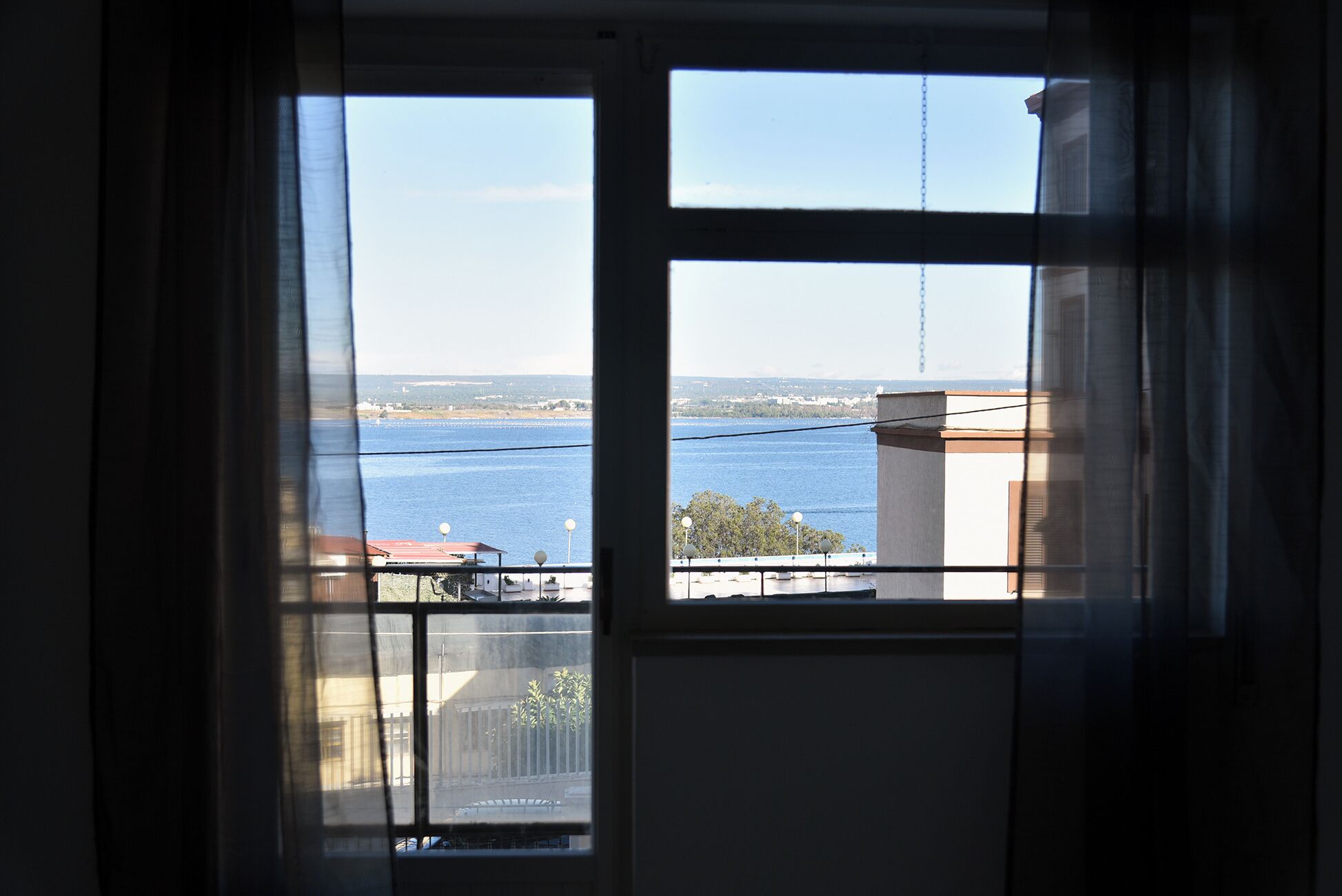 Une vue à travers une fenêtre, avec un ciel dégagé et une étendue d’eau à l’horizon.
