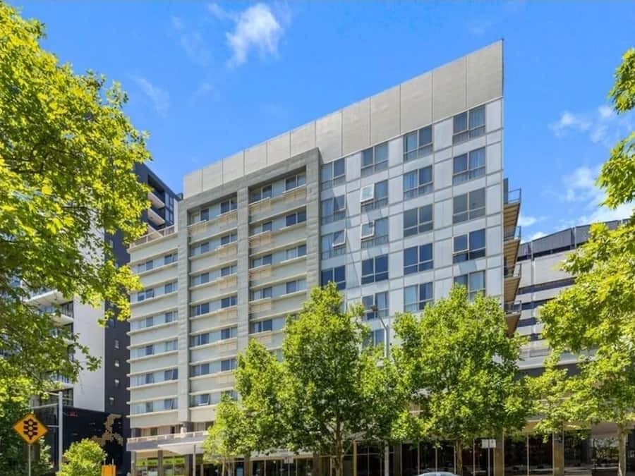 En modern byggnad med flera våningar, en slät fasad, stora fönster och en central entré.
