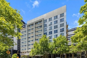 Un edificio moderno de varios pisos con fachada plana, ventanas grandes y una entrada central.
