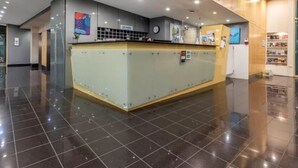 A reception area with a glass counter, a clock, and a wall-mounted sign. - City Central Canberra Unit (Canberra)