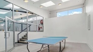 A room with a ping pong table, a staircase, and a large window. - City Central Canberra Unit (Canberra)