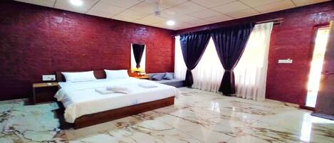 A bedroom with a large bed, a nightstand, a window with curtains, and a red brick wall.