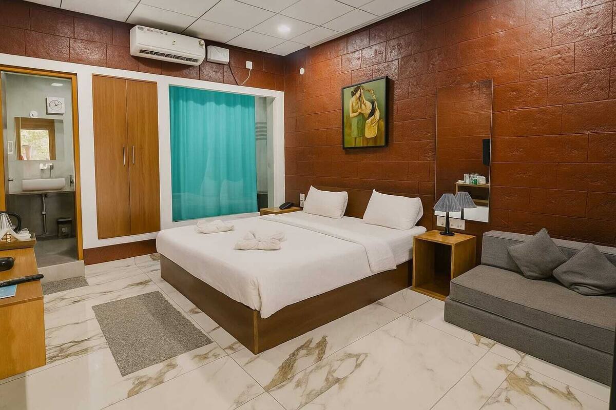 Een hotelkamer met een bed, een bank, een badkamer en een schilderij aan de muur.
