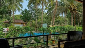Une vue sur la piscine, avec un panneau indiquant « INTERDICTION DE FUMER », le tout entouré d’une végétation luxuriante et de palmiers.