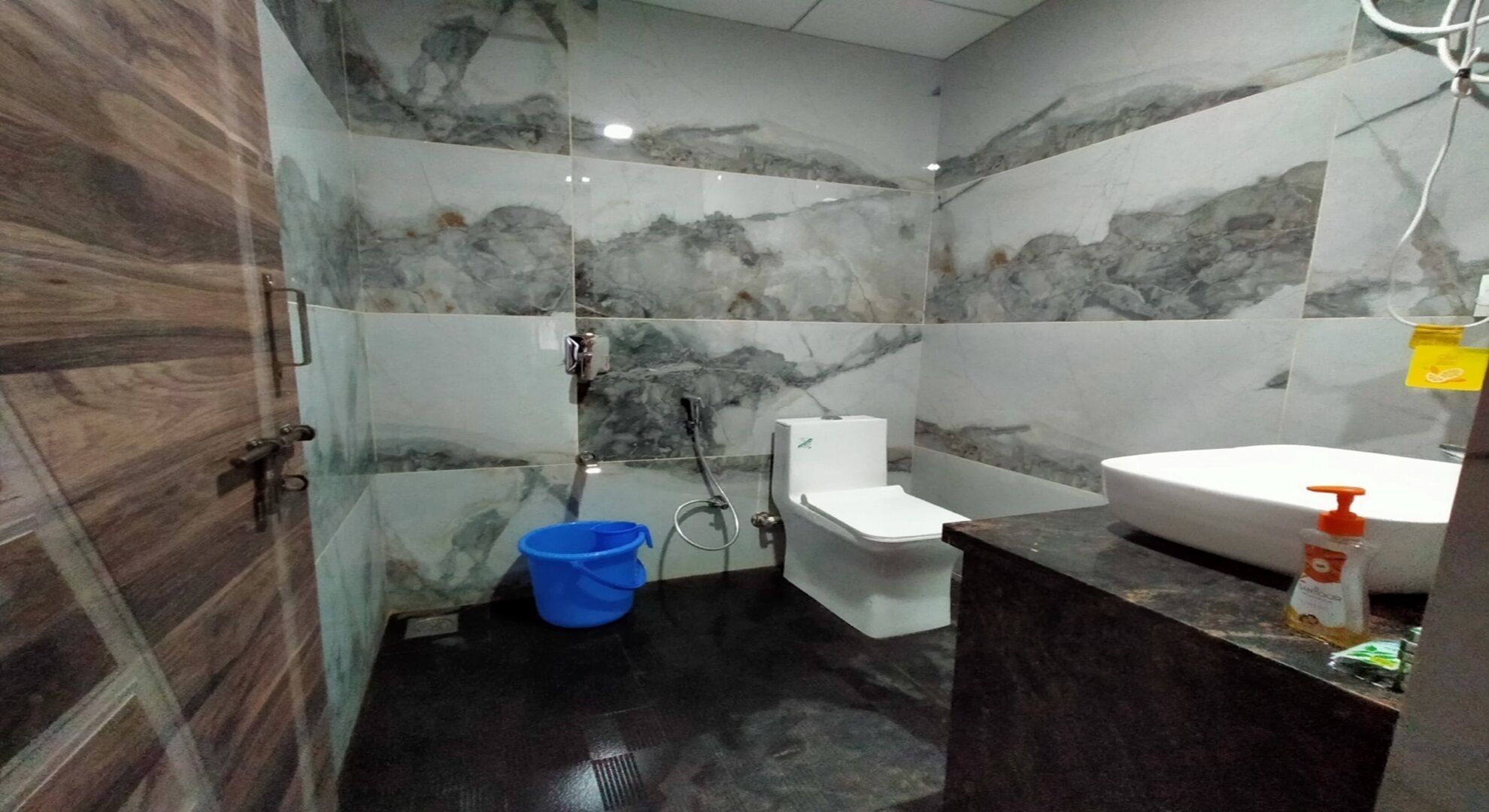 Un baño con paredes de mármol, inodoro, bañera y lavamanos.