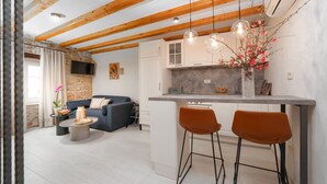 A modern kitchen with a stone accent wall, wooden beams, and pendant lighting. - Modern apartment for 2 persons in the Porec old town , only 150m from the beach. (Porec)