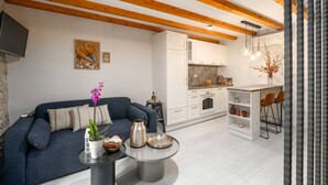 A modern living room with a sofa, a coffee table, and a kitchen area with white cabinets and a bar. - Modern apartment for 2 persons in the Porec old town , only 150m from the beach. (Porec)
