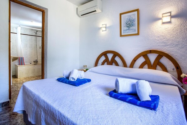 A hotel room with a bed, a bathroom, and a painting on the wall. - Agradable Villa con Piscina (Xàbia)