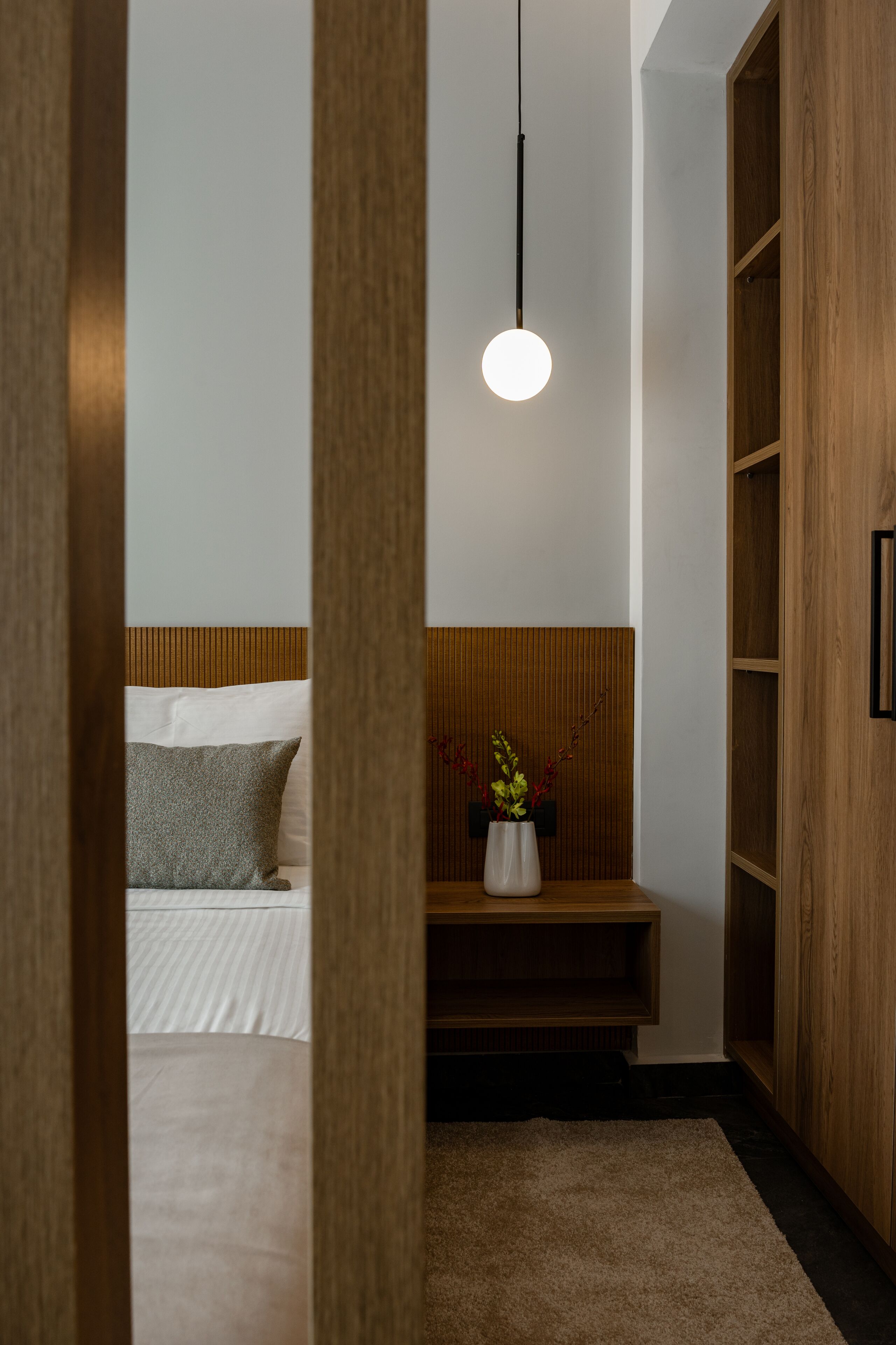 Un dormitorio con cama, mesita de noche y armario de madera.