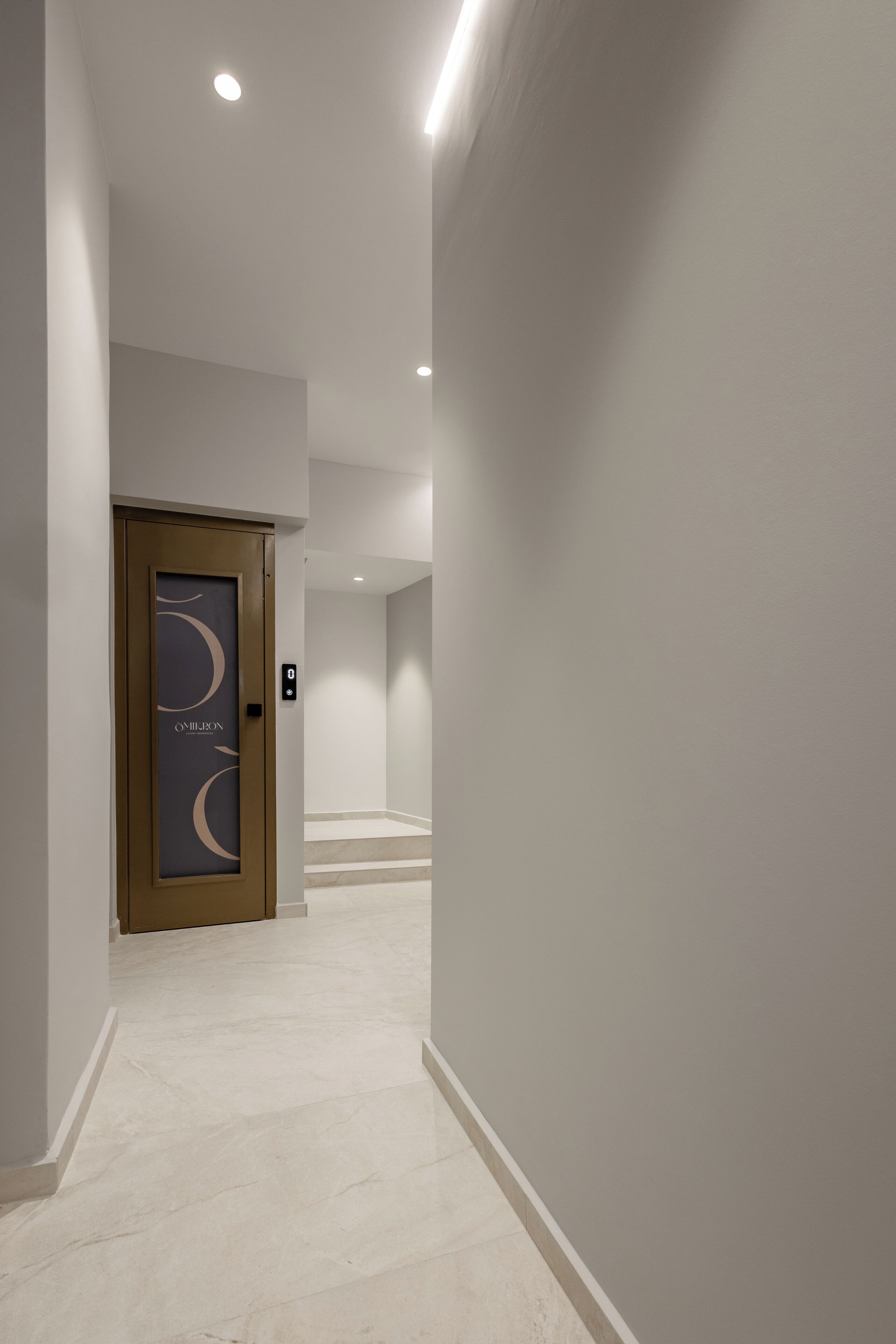 A modern hallway with a door featuring a crescent moon design, a light-colored floor, and recessed ceiling lighting.