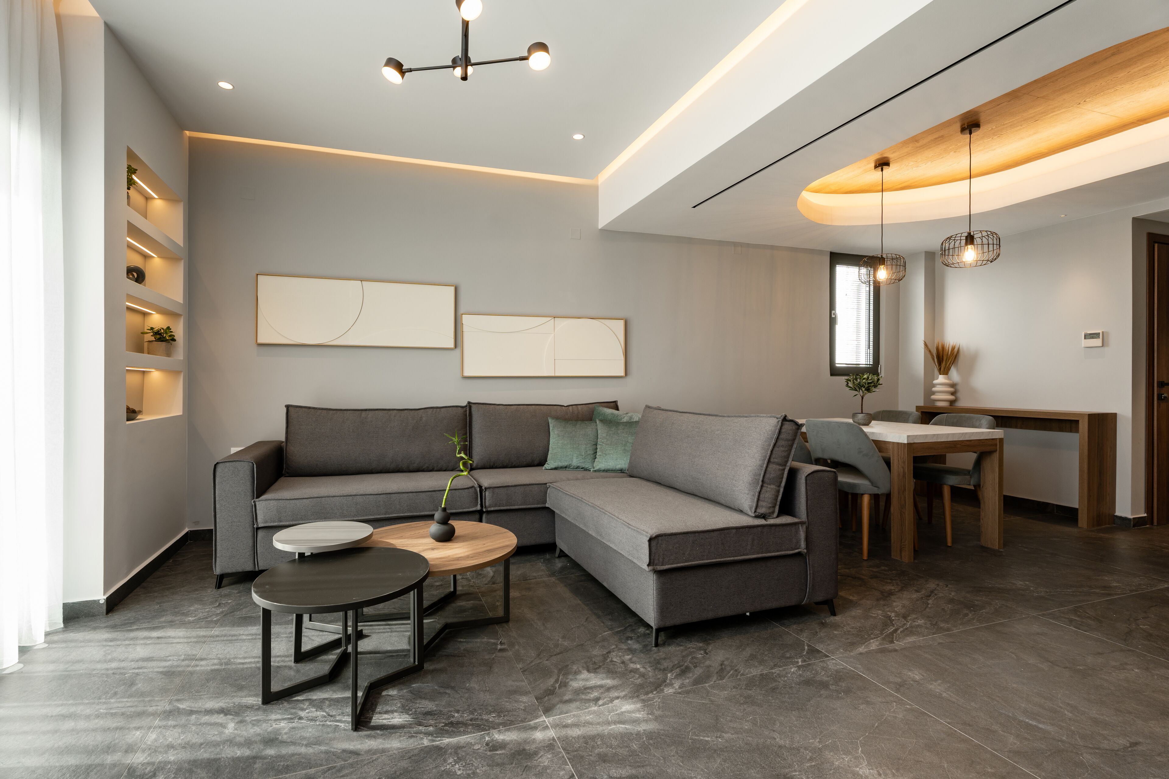 A modern living room with a sectional sofa, a round coffee table, and a dining area with a wooden table and chairs.