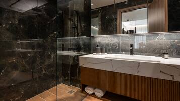 A modern bathroom with a glass-enclosed shower, a wooden vanity, and a large mirror.