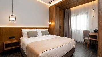 Een moderne hotelkamer met een groot bed, houten lambrisering, een bureau en een stoel.