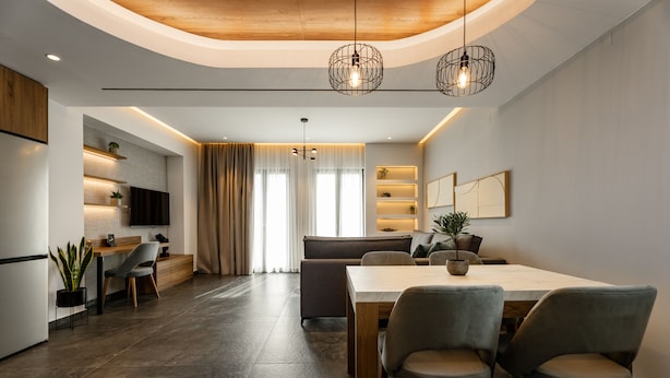 A modern kitchen with a dining area, wooden ceiling, and pendant lighting.