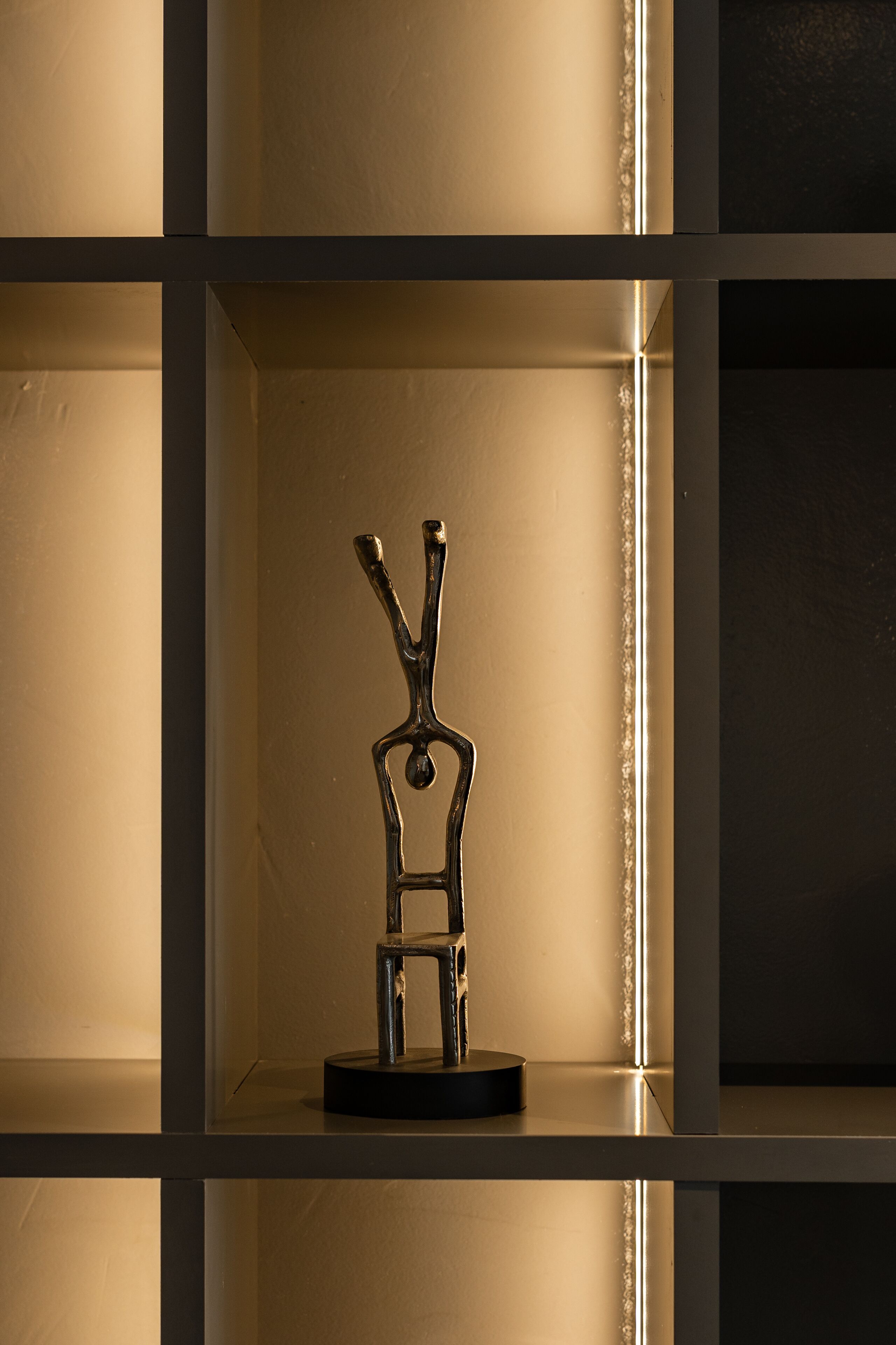 A sculpture on a shelf in a room with a minimalist design.