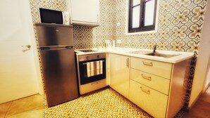 Una cocina compacta equipada con refrigerador, horno, microondas y pileta.