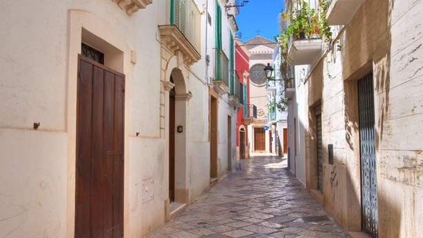 A narrow street with buildings on either side, featuring stone-paved ground and traditional architecture. - Pianista Home in Fasano City (Fasano)