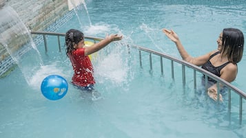 A swimming pool with clear water, a metal railing, and a blue ball.