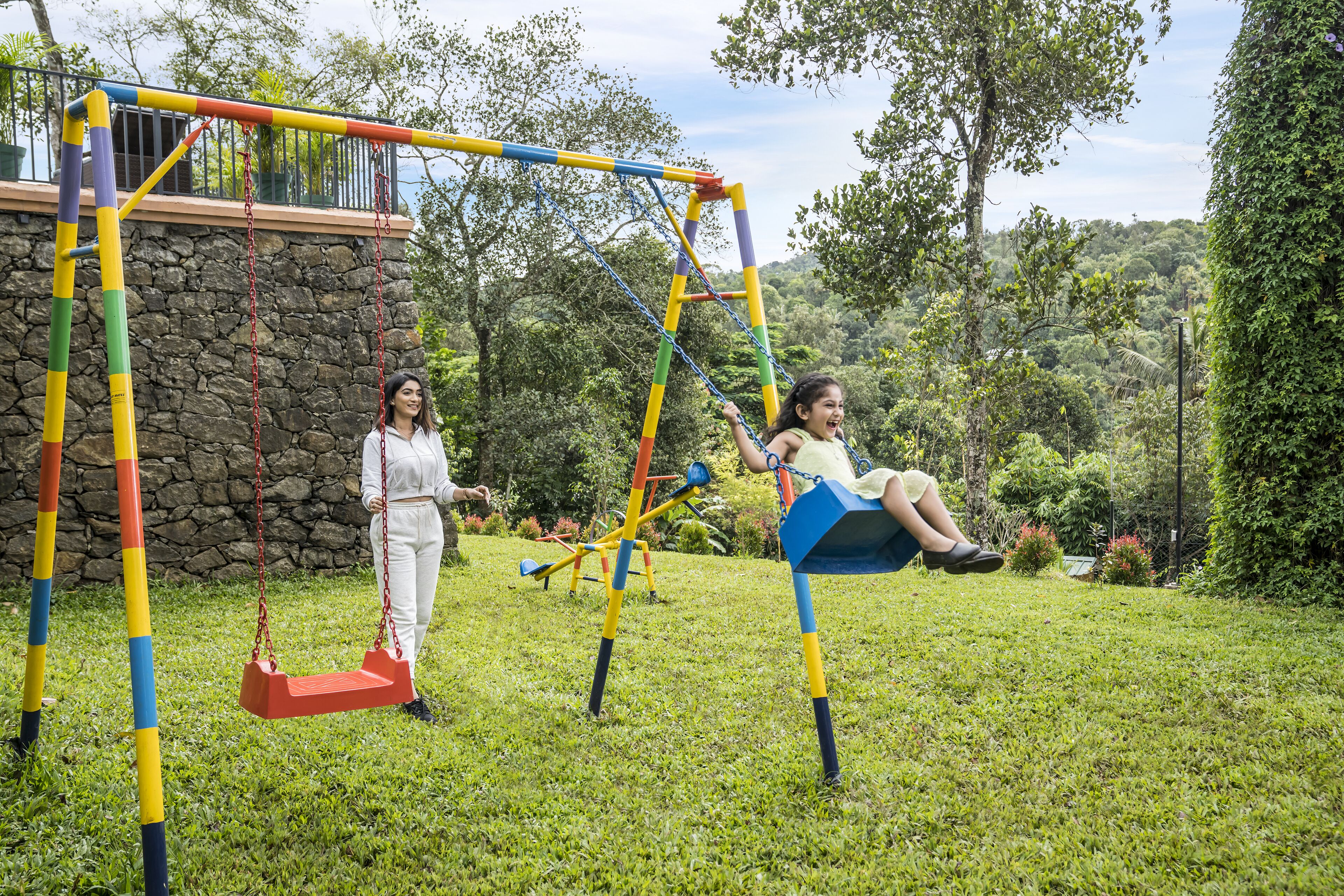 En legeplads med gynger og en stenvæg i baggrunden.
