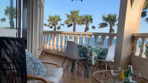 Ein Balkon mit einem Tisch für zwei Personen, Stühlen und einem Korbstuhl.