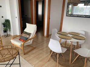 A modern living room with a sofa, a dining table with chairs, and a large mirror.