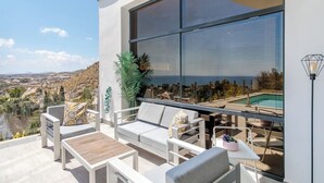 Un espace extérieur moderne, aménagé avec des sièges, une piscine, du mobilier blanc et offrant une vue panoramique.