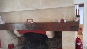 A stone fireplace with a wooden mantel, a framed picture, and two red candle holders. - Spacious villa in theAude close to the sea, mountains, history and vineyards! (Montazels)