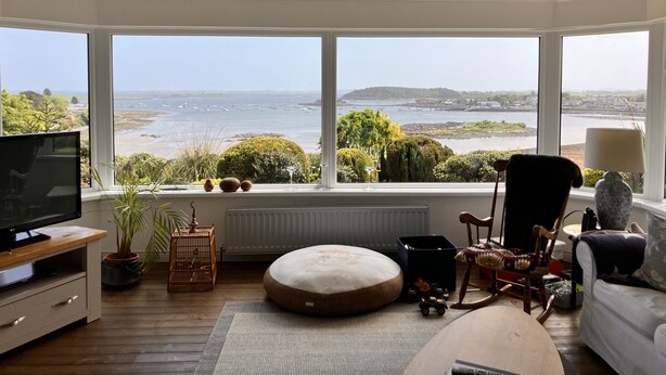 A spacious living room with a large bay window offering a scenic view of the sea and hills. - Ballydorn Lodge Strangford Lough (Killinchy)