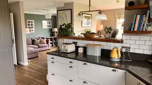 A modern kitchen with white cabinetry, a wooden countertop, and a yellow kettle. - Ballydorn Lodge Strangford Lough (Killinchy)