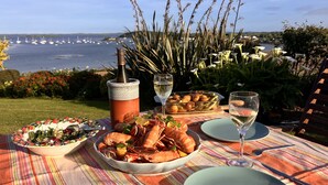 A table set with seafood, a bottle, and glasses of wine, overlooking a marina. - Ballydorn Lodge Strangford Lough (Killinchy)