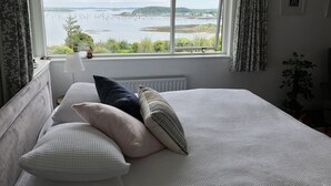 A bedroom with a large window offering a view of a lake and distant land. - Ballydorn Lodge Strangford Lough (Killinchy)