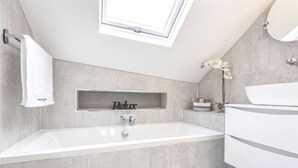A modern bathroom with a freestanding bathtub, a skylight, and a minimalist design.