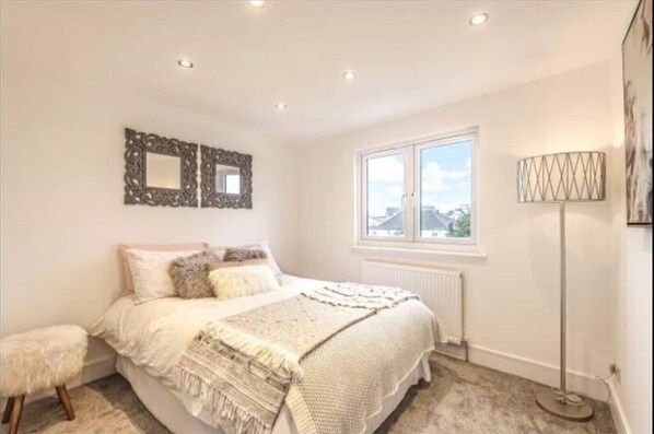 A bedroom with a bed, a window, a radiator, and a floor lamp. - Luxury 3 Bedroom House in Bromley, South East London (Bromley)
