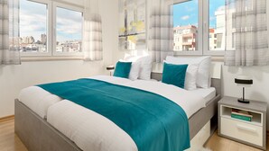 A modern bedroom with a large bed, two bedside tables, and a view of the city through large windows. - Sun Spalato Flower (Split)