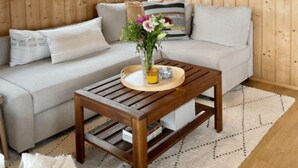 Un interior de madera con un sofá, una mesa con un florero y una lámpara colgante.