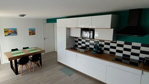 A compact kitchen with white cabinets, a wooden countertop, and a black and white checkered backsplash. - Appartement Neuf, à 5minutes de la Plage, Commerce au Rdc, Pour 4 Personnes (Plounéour-Brignogan-plages)