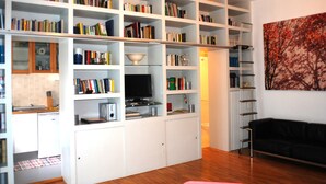 A living room with a white entertainment unit filled with books and a television. - Carlo's welcome in Trastevere (Roma)