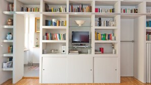 A modern living room with a built-in TV, bookshelves, and a glass coffee table. - Carlo's welcome in Trastevere (Roma)
