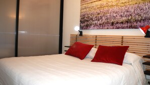 A bedroom with a bed, red pillows, a nightstand, a lamp, and a wall-mounted TV. - Carlo's welcome in Trastevere (Roma)