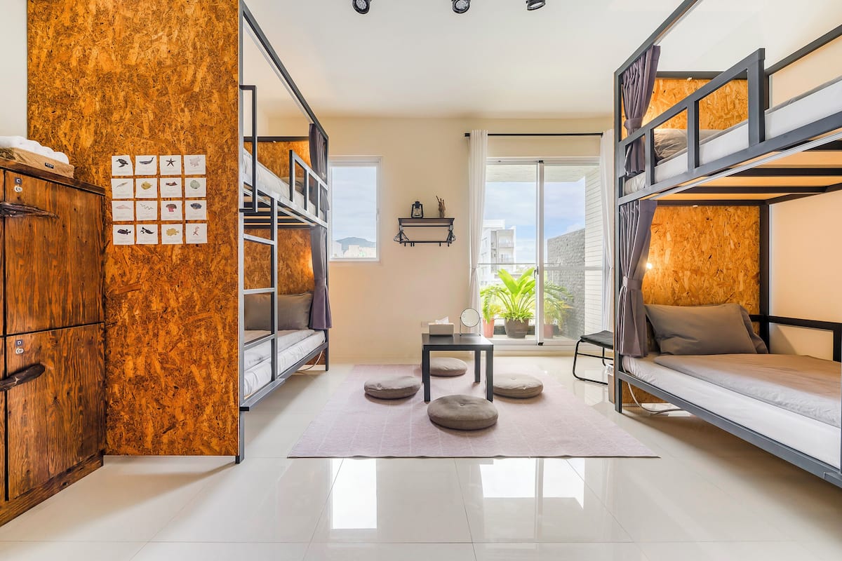 A compact room with bunk beds, a wooden cabinet, a small table, and a window with a view.