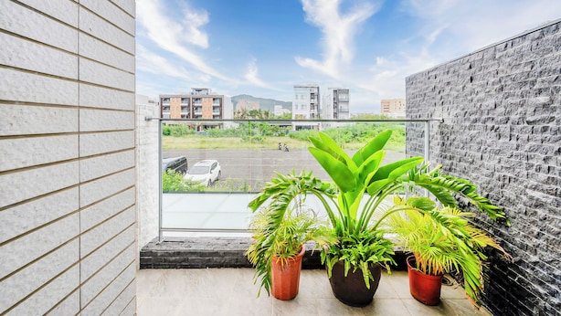 A balcony with potted plants, a view of a parking lot, and buildings in the background. - Stay in Jialeshuei (Hengchun)
