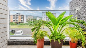 A balcony with potted plants and a view of buildings and a parking lot. - Stay in Jialeshuei (Hengchun)