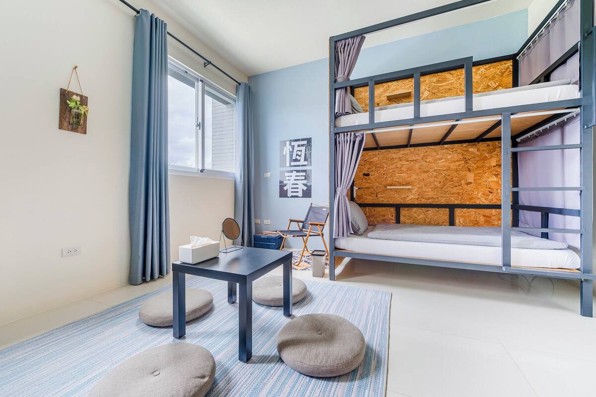 A room with bunk beds, a small table, and a chair.