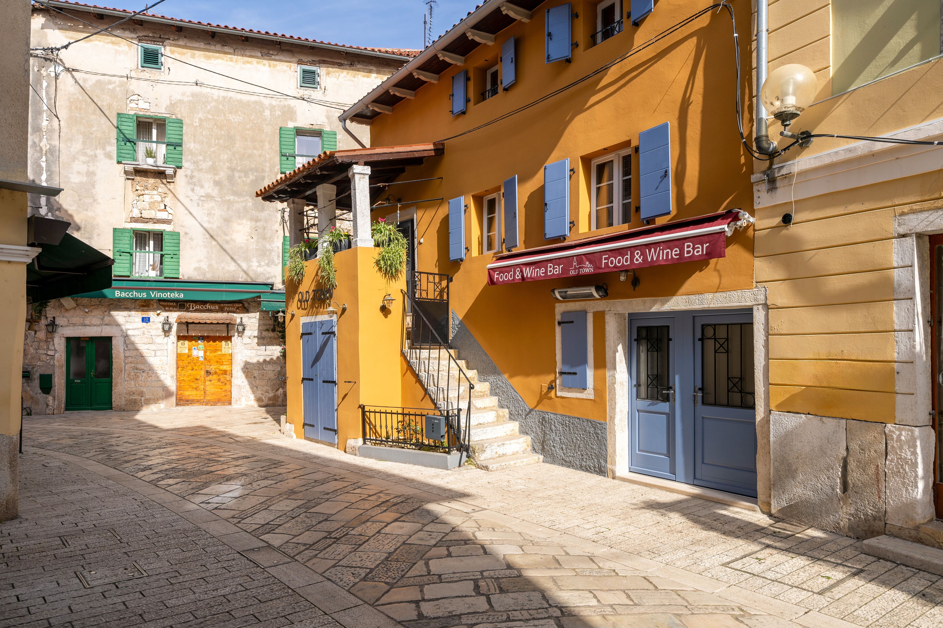 Une rue bordée d’immeubles, dont un bar proposant des plats et une sélection de vins.