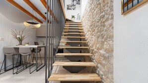 Una escalera moderna con escalones de madera y barandillas metálicas que conduce a un comedor con mesa y sillas.