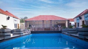 Une piscine à l’eau d’un bleu cristallin, entourée de chaises longues et d’un espace de détente abrité.