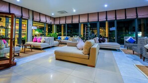 A spacious living area with multiple sofas and armchairs, large windows, and a visible outdoor view. - Azura Golf Resort & Spa (Mahavelona)
