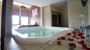 A large indoor swimming pool with a statue, a shower, and rose petals on the floor. - Azura Golf Resort & Spa (Mahavelona)